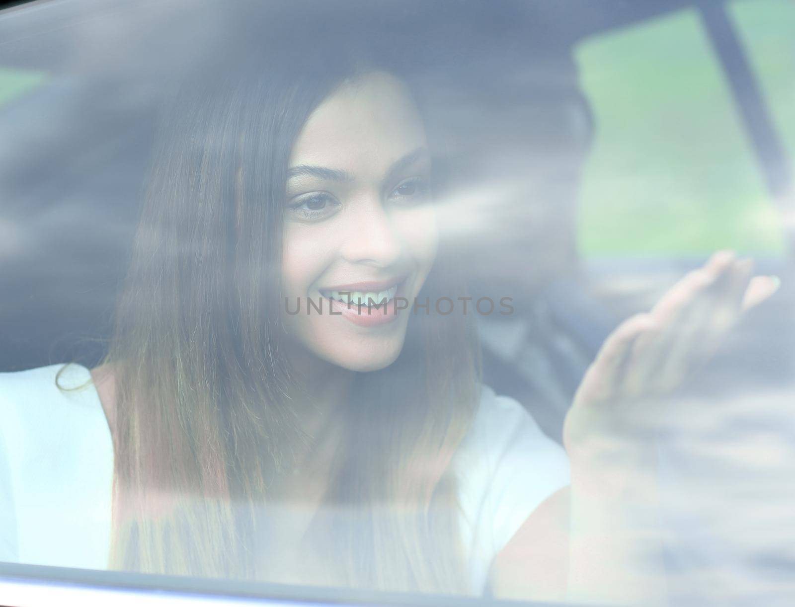 Woman sitting in car behind window, tinted photo