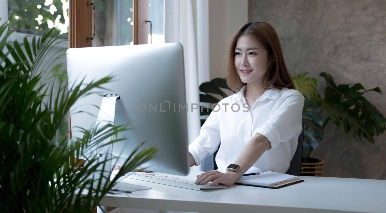 Charming asian businesswoman sitting working on laptop in office..