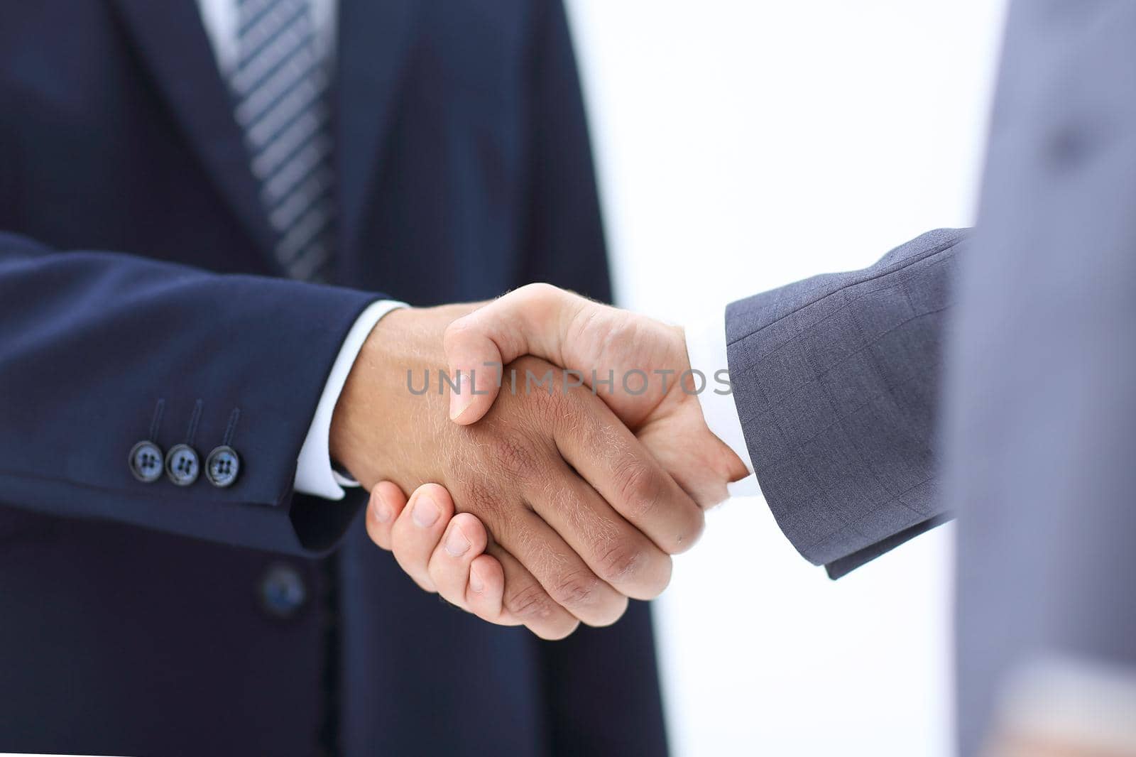 Two young businessman standing opposite each other and shake their hands.