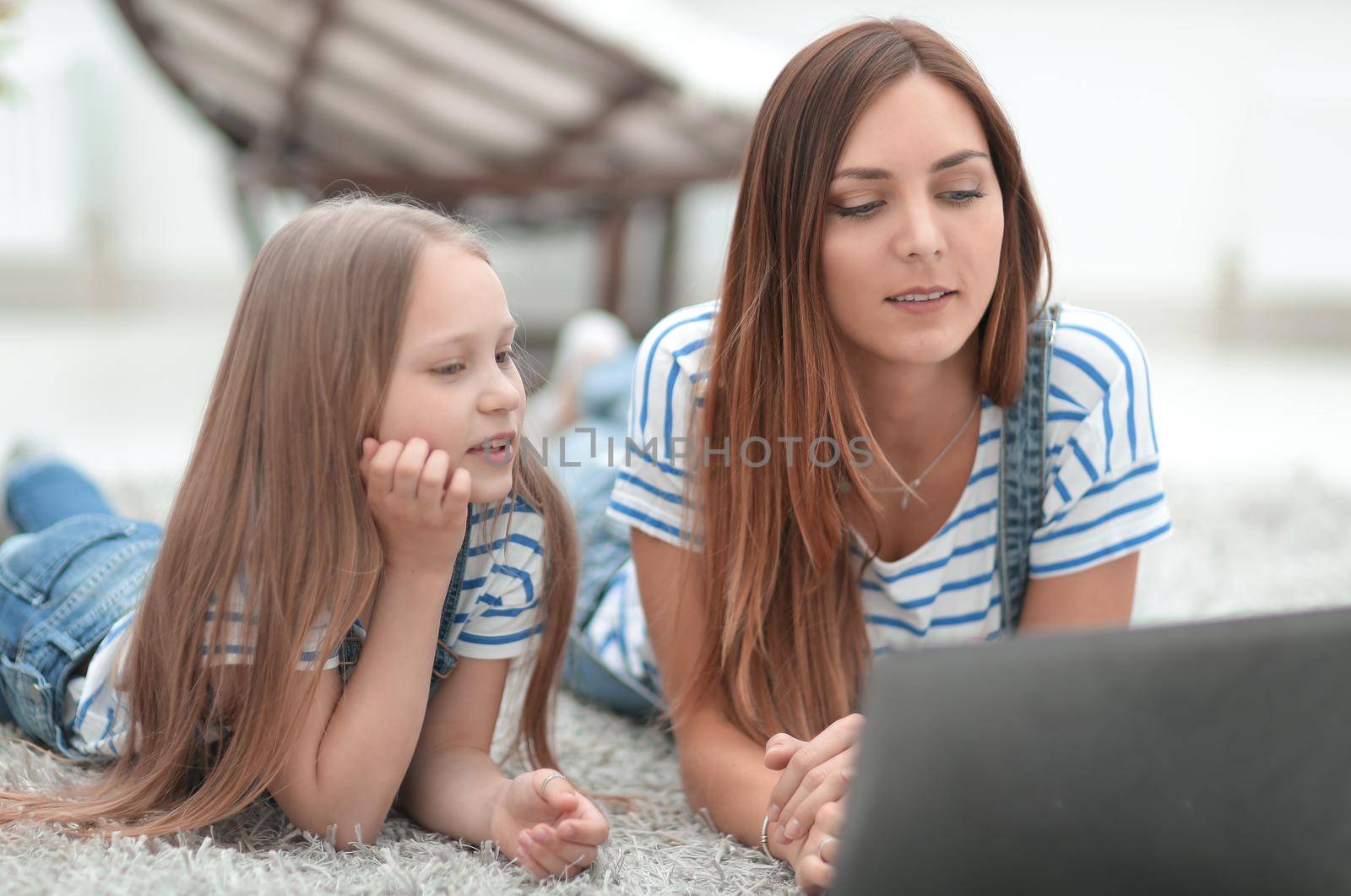 mother and daughter looking at the laptop screen. by asdf