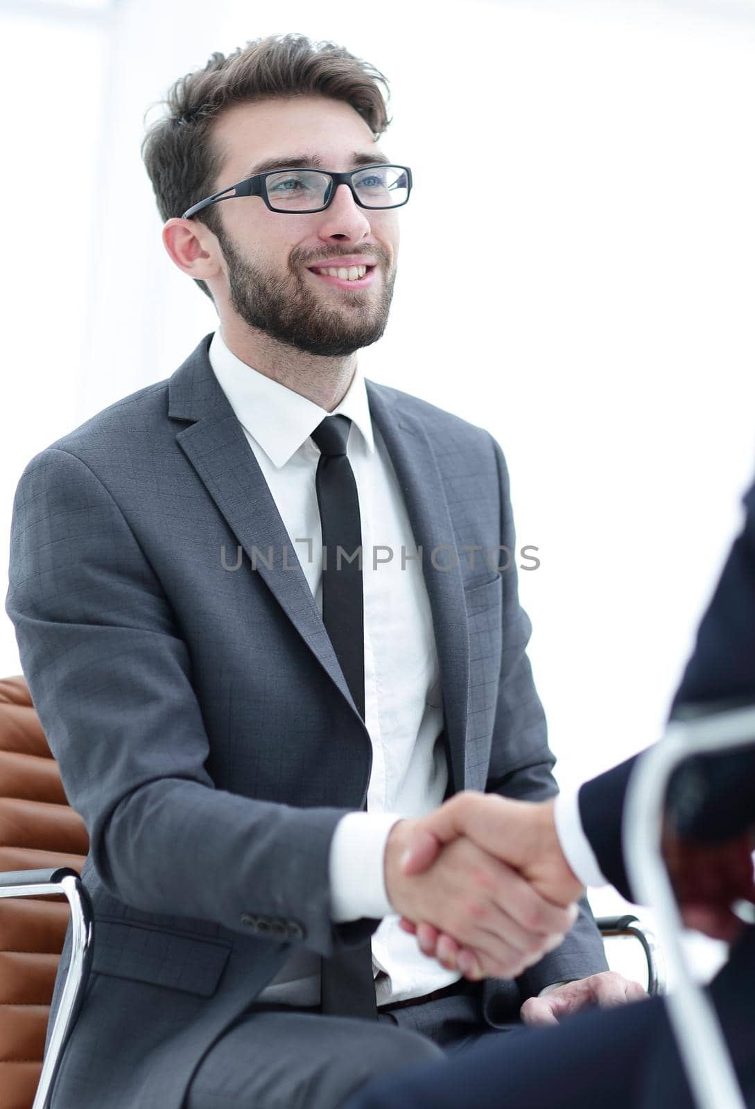 Image of two young businessmen interacting at meeting in office