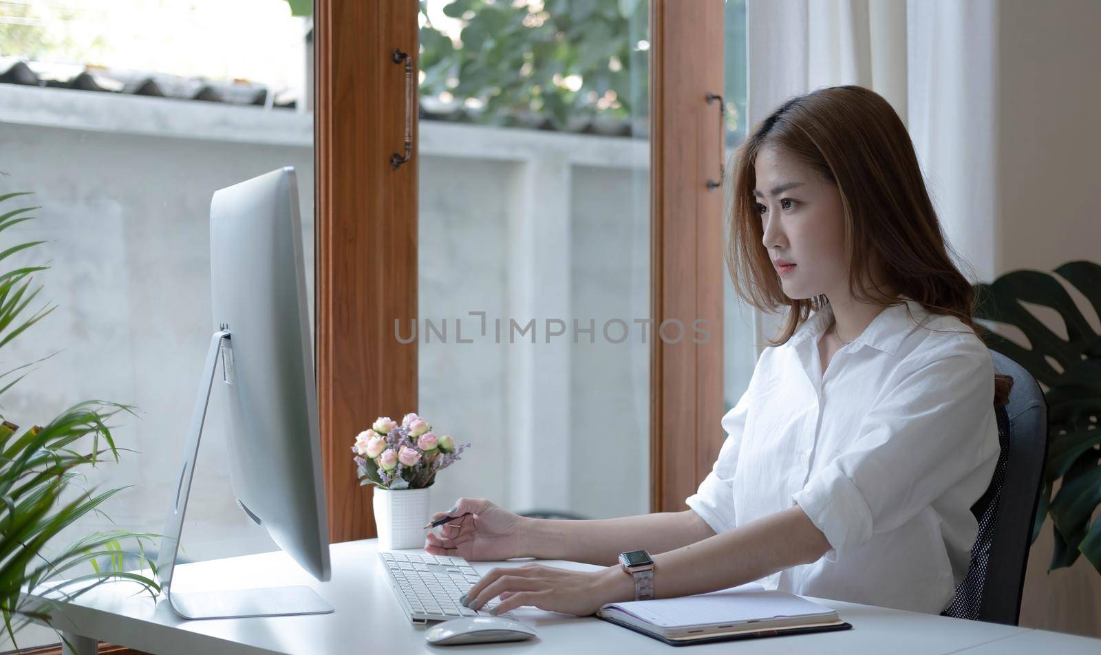 Image of an Asian woman who is tired and overthinking from working with a tablet at the office. by wichayada