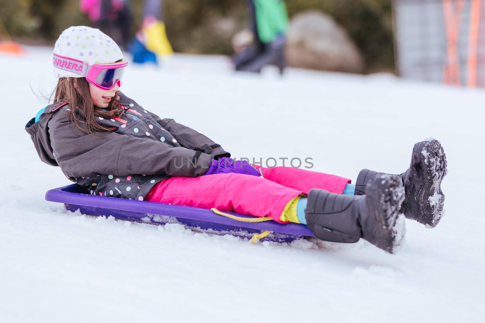 A young girl tobogganing at Lake Mountain on a clear sunny day in Victoria, Australia