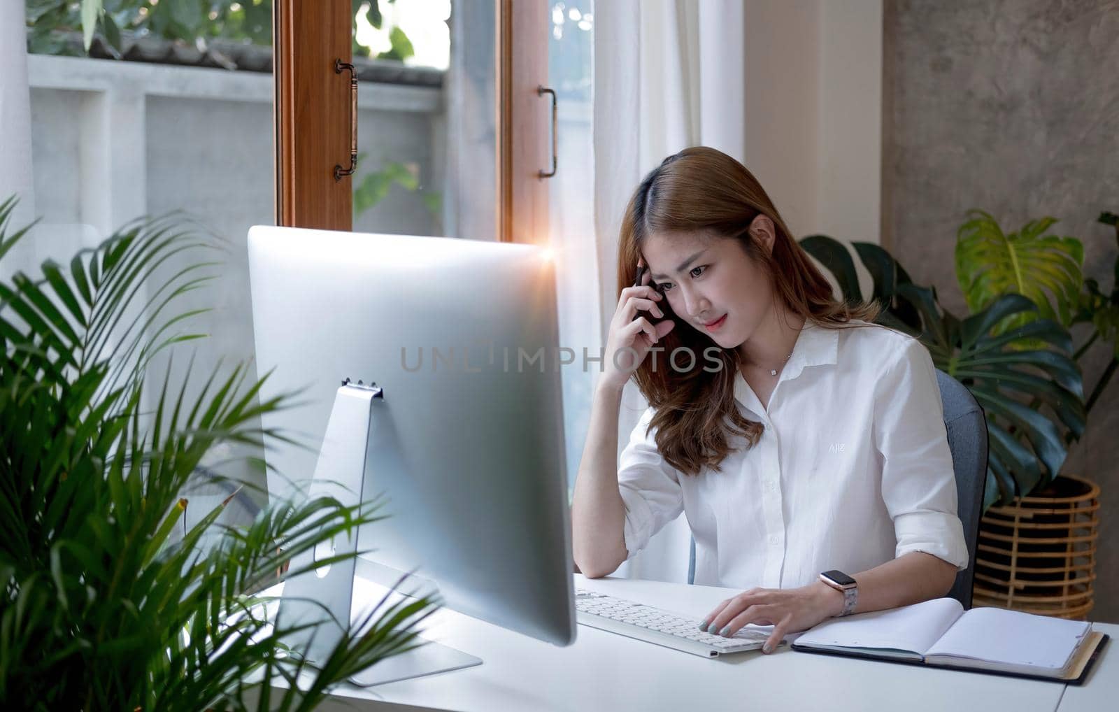 Charming asian businesswoman sitting working on laptop in office. by wichayada