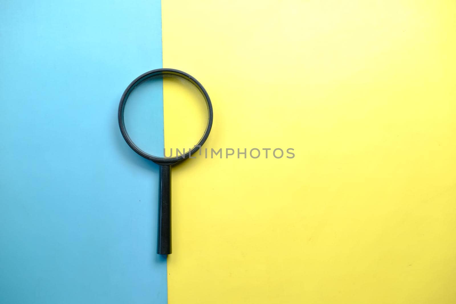 a magnifying glass on color background top view .