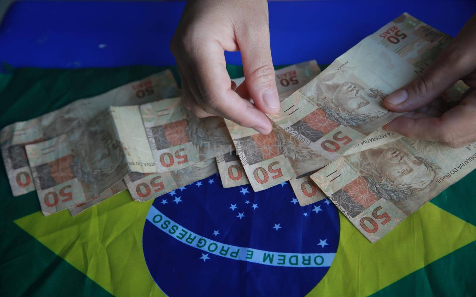 salvador, bahia, brazil - april 3, 2022: fifty reais banknotes next to a brazil flag.
