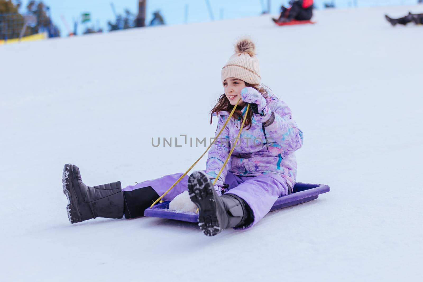 A young girl tobogganing at Lake Mountain on a clear sunny day in Victoria, Australia