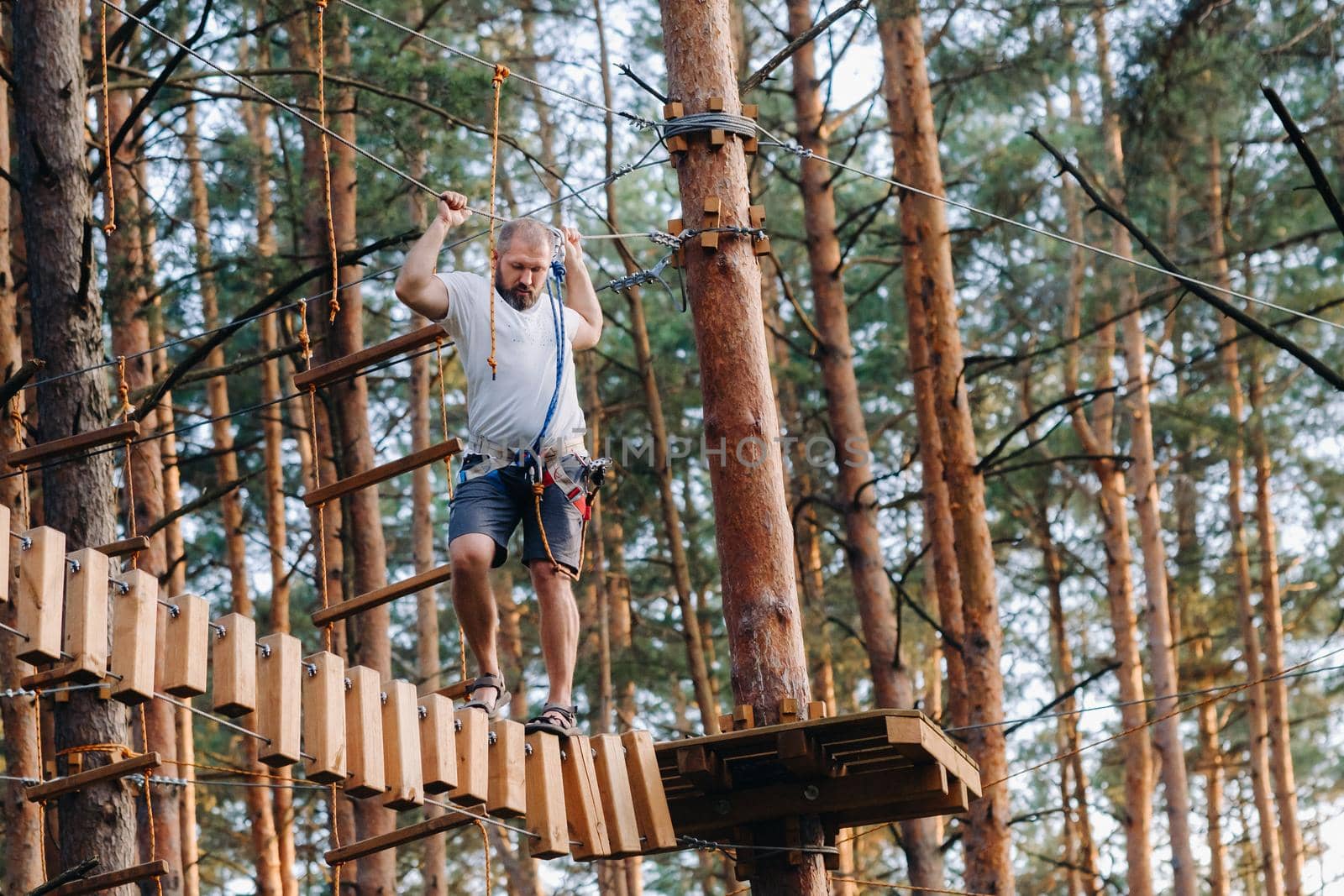 A man overcomes an obstacle in a rope town. A man in a forest rope park.