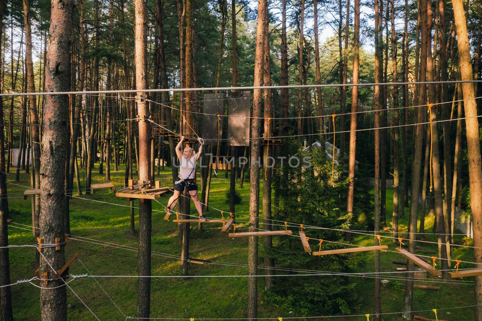 A woman overcomes an obstacle in a rope town. A woman in a forest rope park.