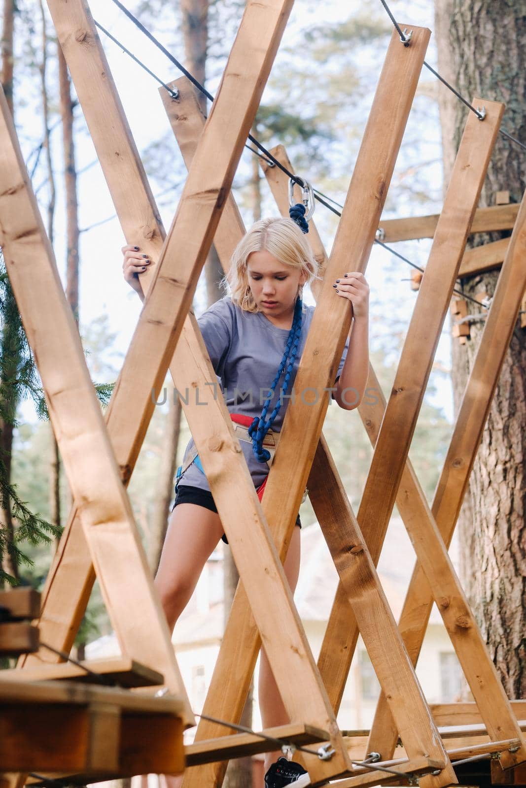 A girl passes an obstacle in a rope town. A girl in a forest rope park by Lobachad
