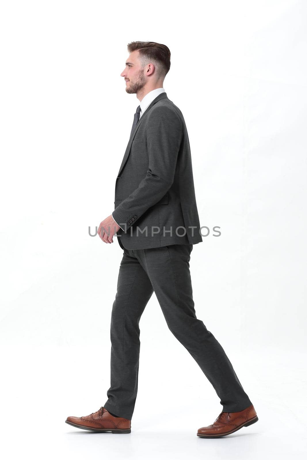 side view. the young businessman confidently steps forward .isolated on white background