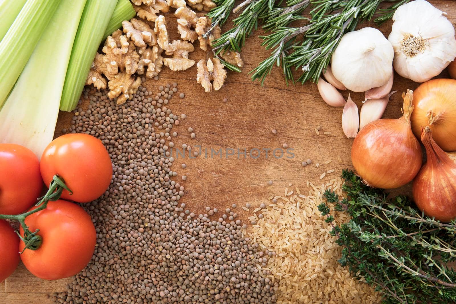 Healthy food frame with fresh vegetables, herbs and grains on rustic wooden background viewed from above.