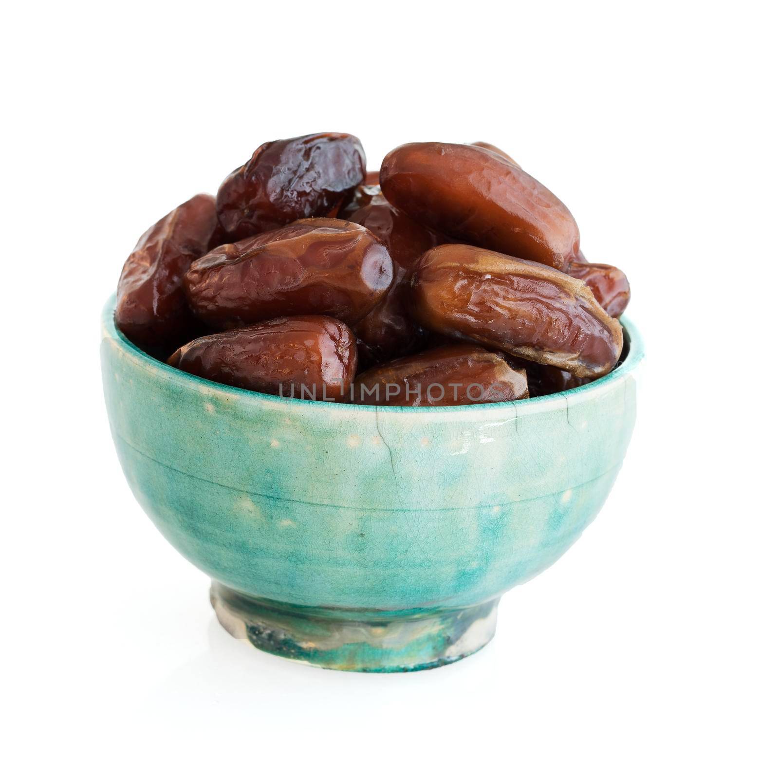 Dates in green bowl isolated on white.