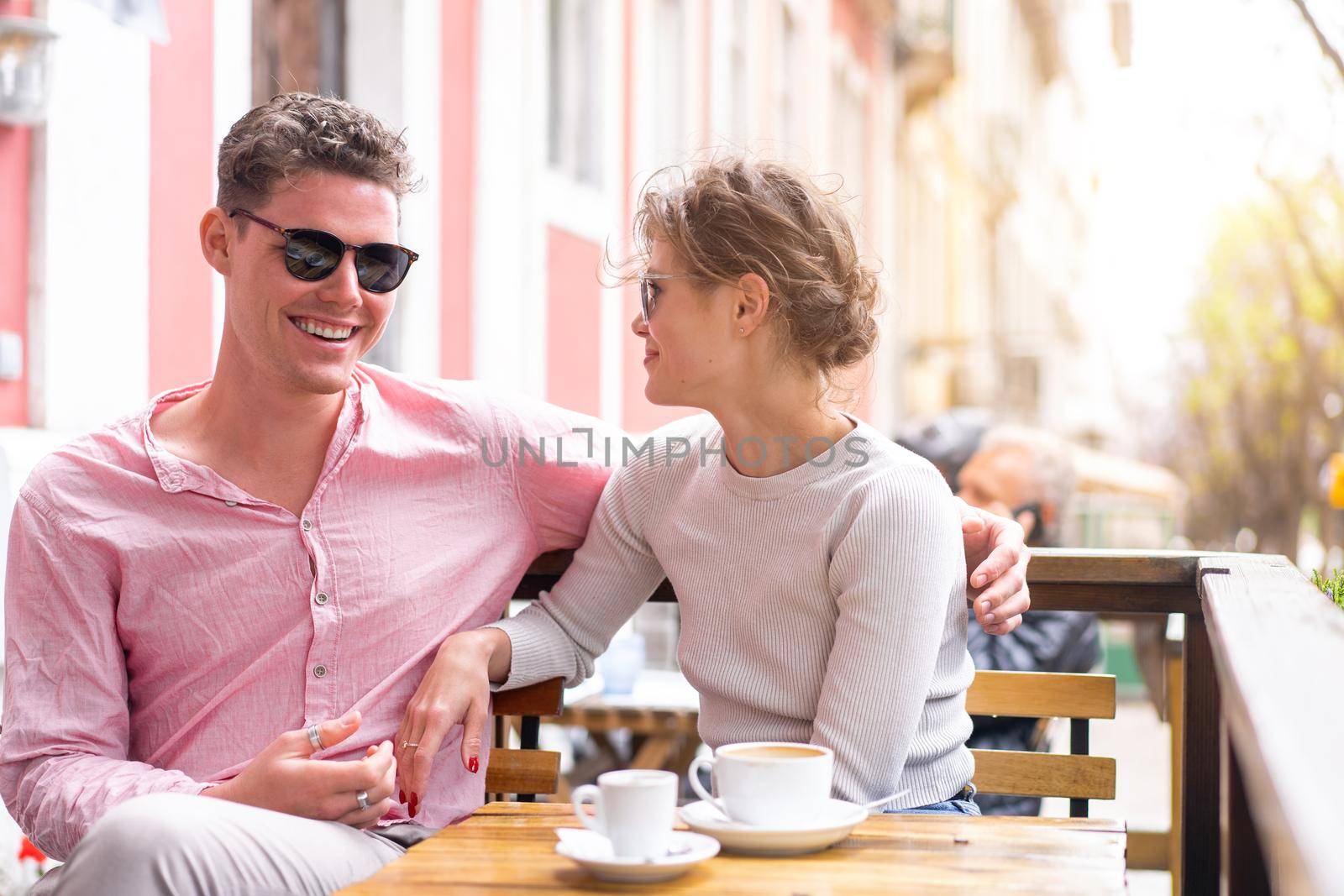 Flirting in a cafe. Beautiful loving couple sitting in a cafe drinking coffee and enjoying in conversation. Love, romance, dating. Man and woman sitting outside cafeteria enjoy coffee