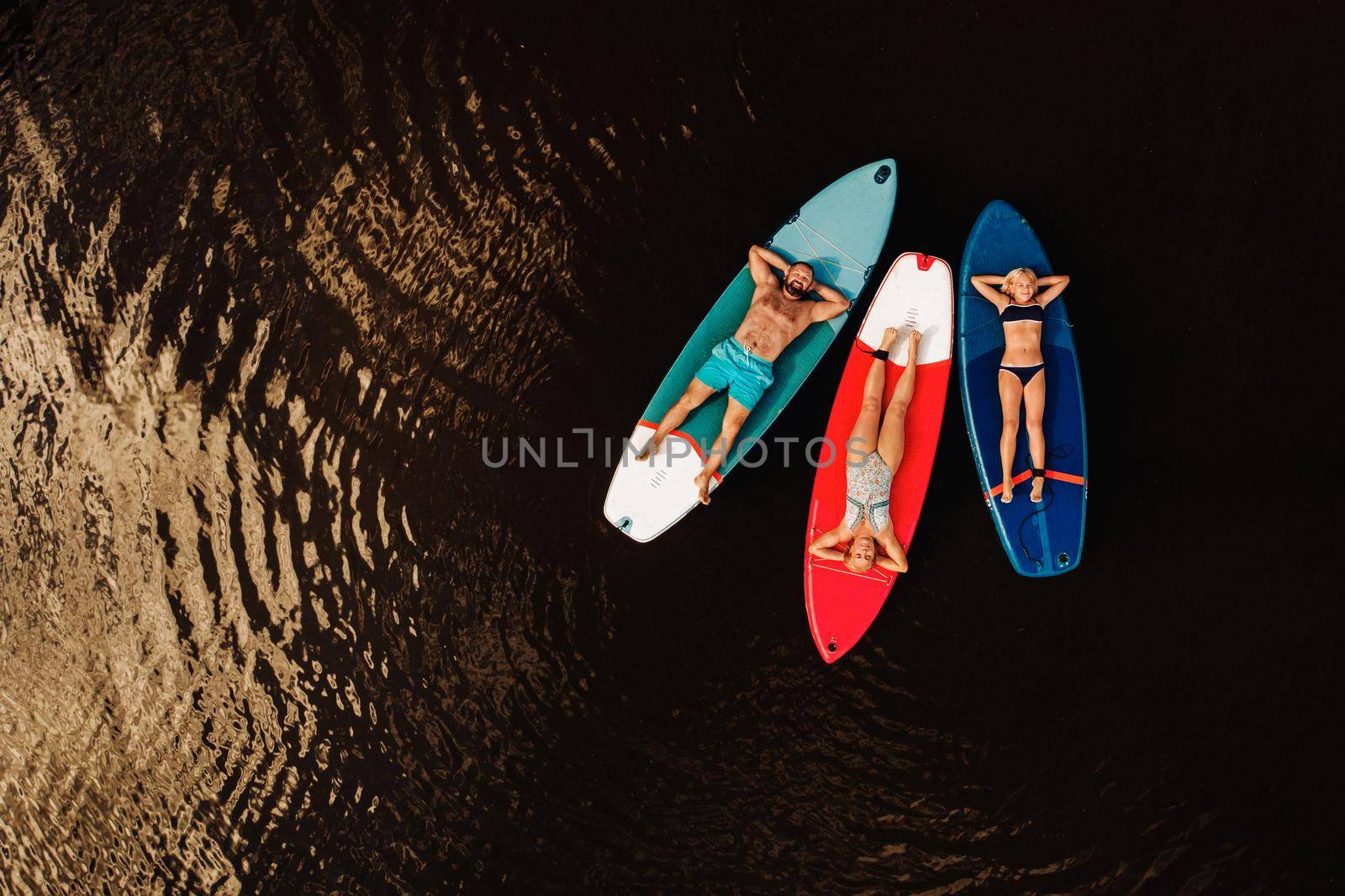 Family spend time together relaxing on sup boards on the lake.