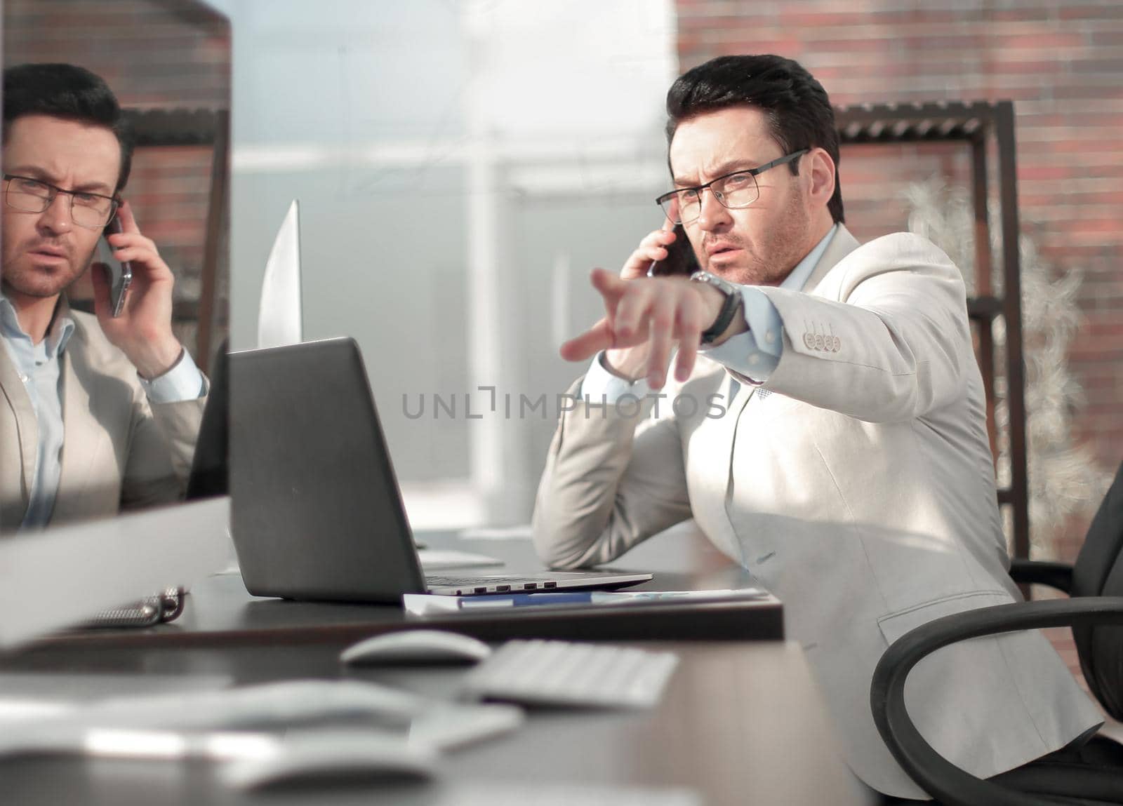 businessman talking on a mobile phone, sitting at the office table.