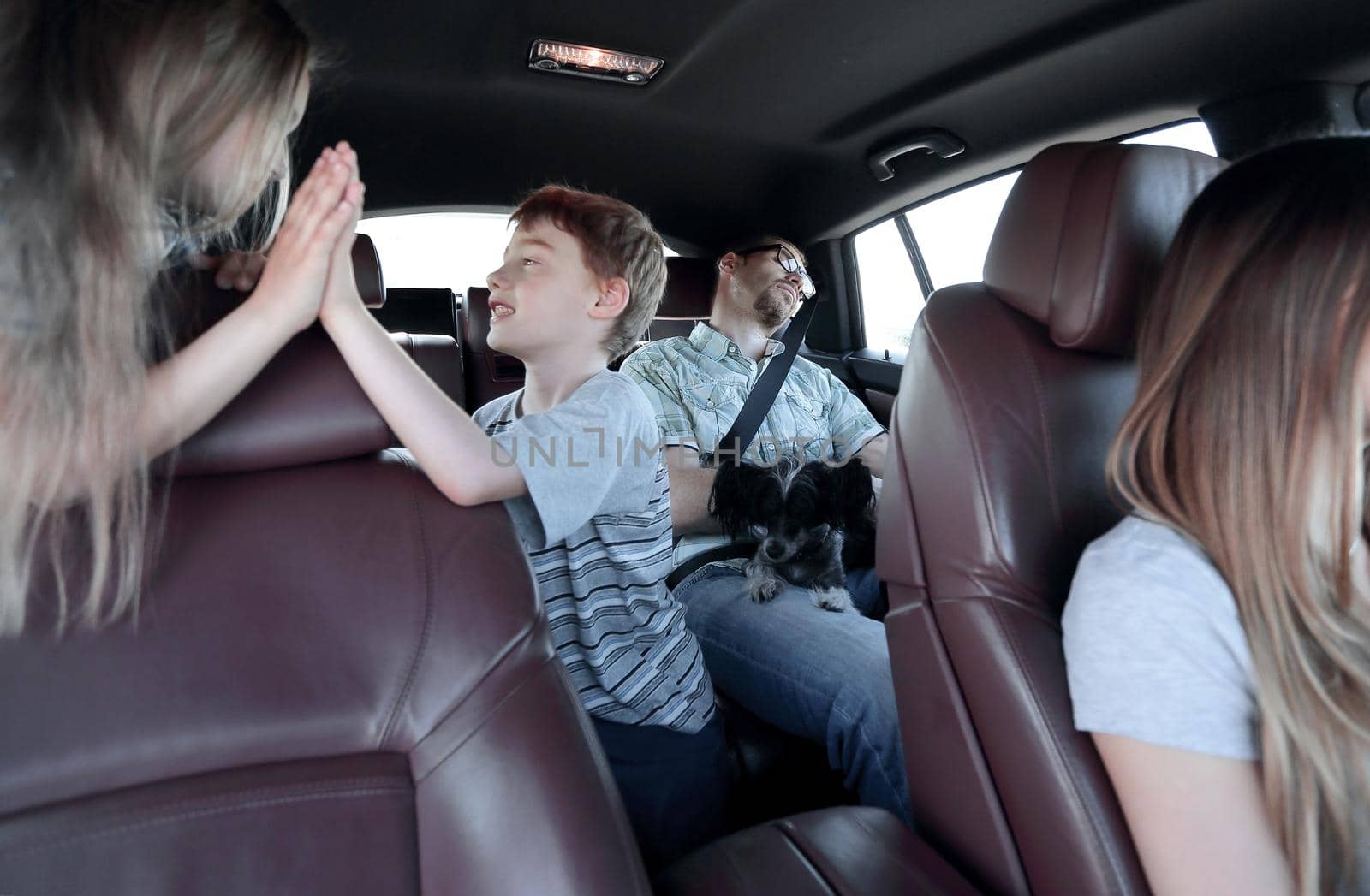 brother and sister give a high five while sitting in the car cabin.family holiday concept