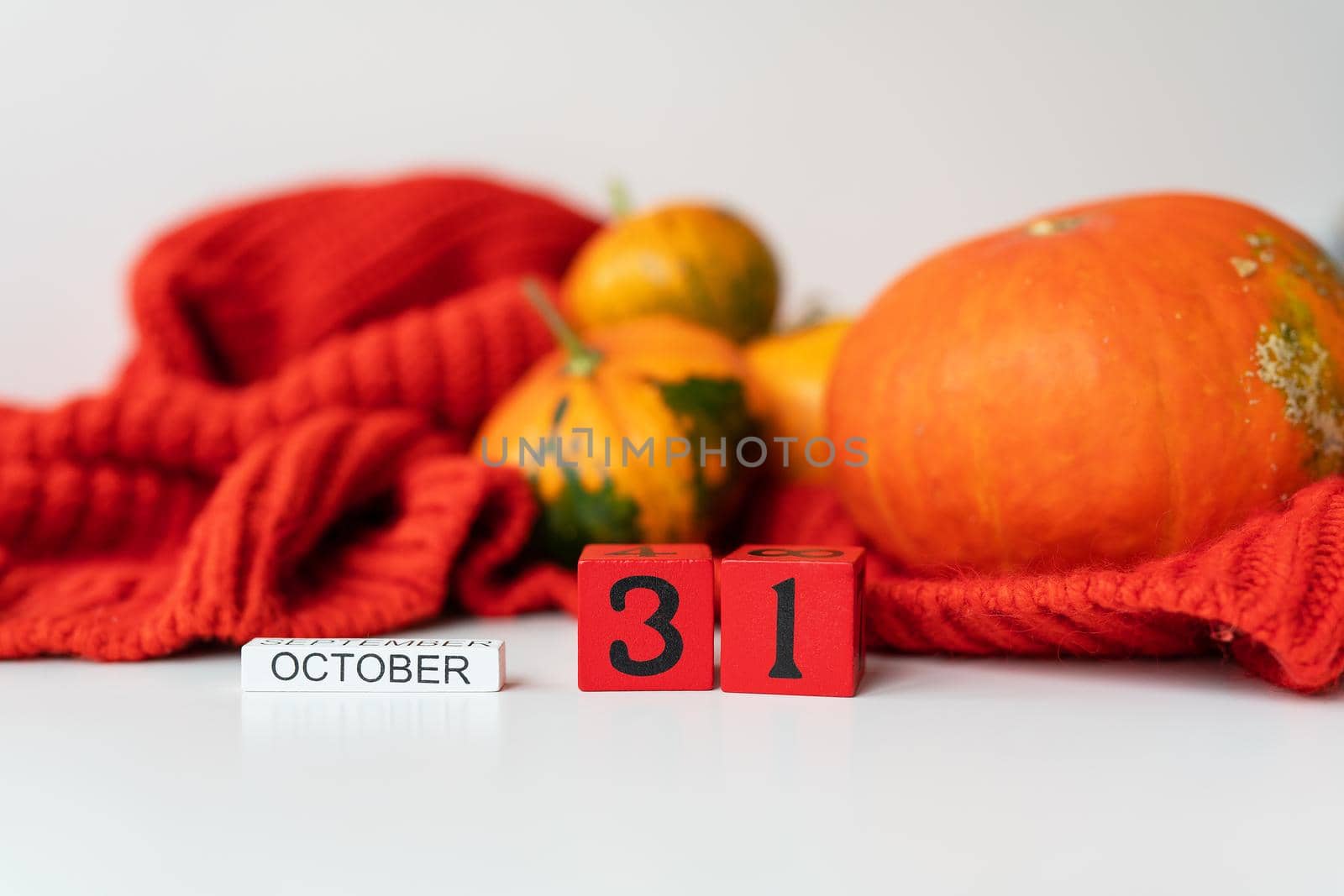 Wooden cube calendar showing Halloween October 31st, with pumpkins in the background. Holiday and party concept. by sfinks