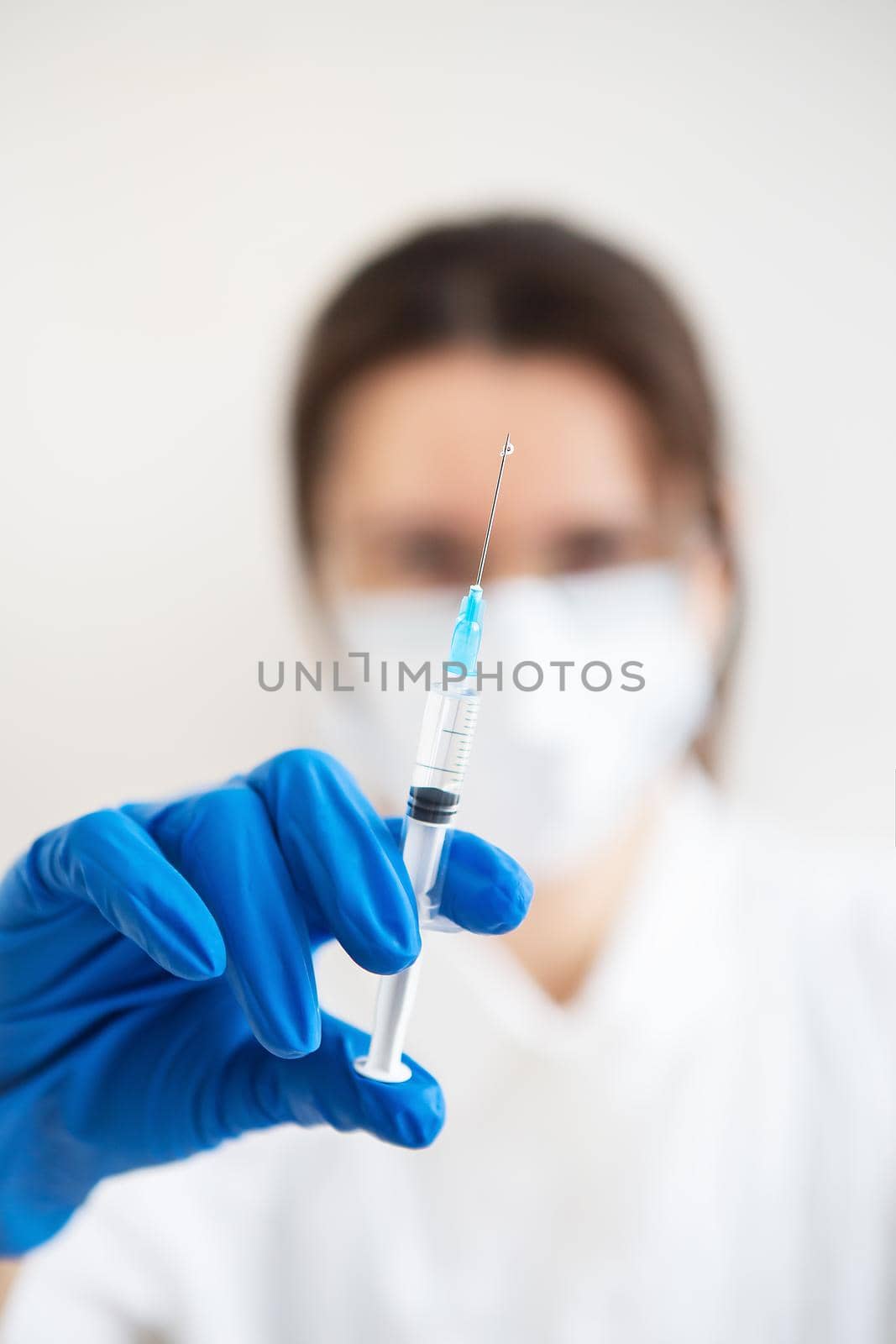 Young doctor with a syringe in his hands. Doctor indoors makes vaccination. A woman in a medical office. Vaccination against influenza and viruses