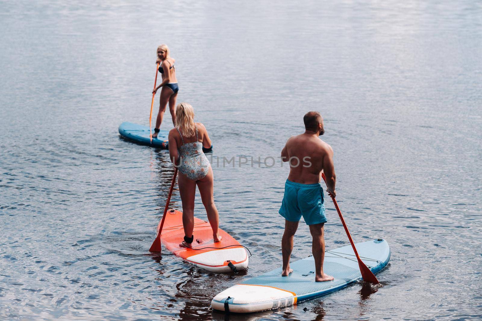 The family spends time together swimming on sup boards on the lake.