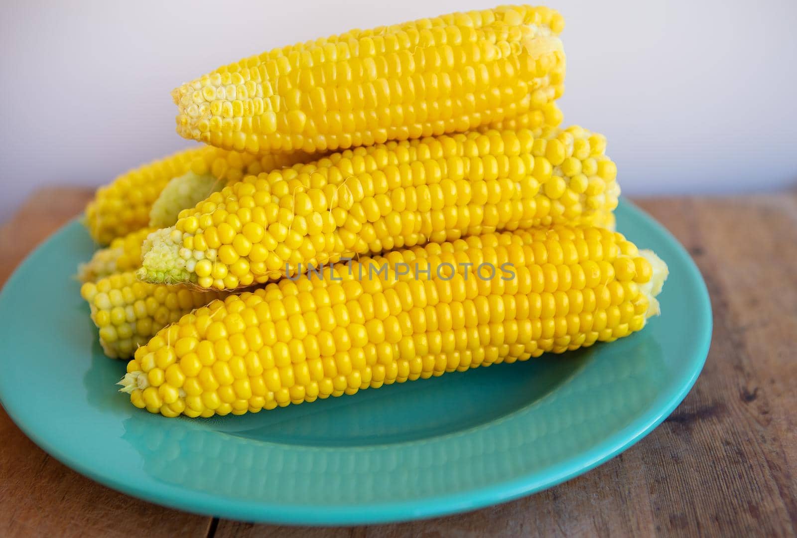 Boiled corn cobs lie on a green plate. Delicious and juicy corn. by sfinks