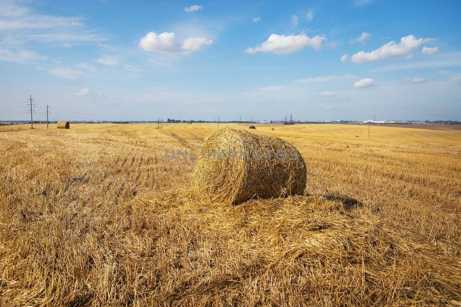 Straw bales on farmland with blue beautiful sky with clouds