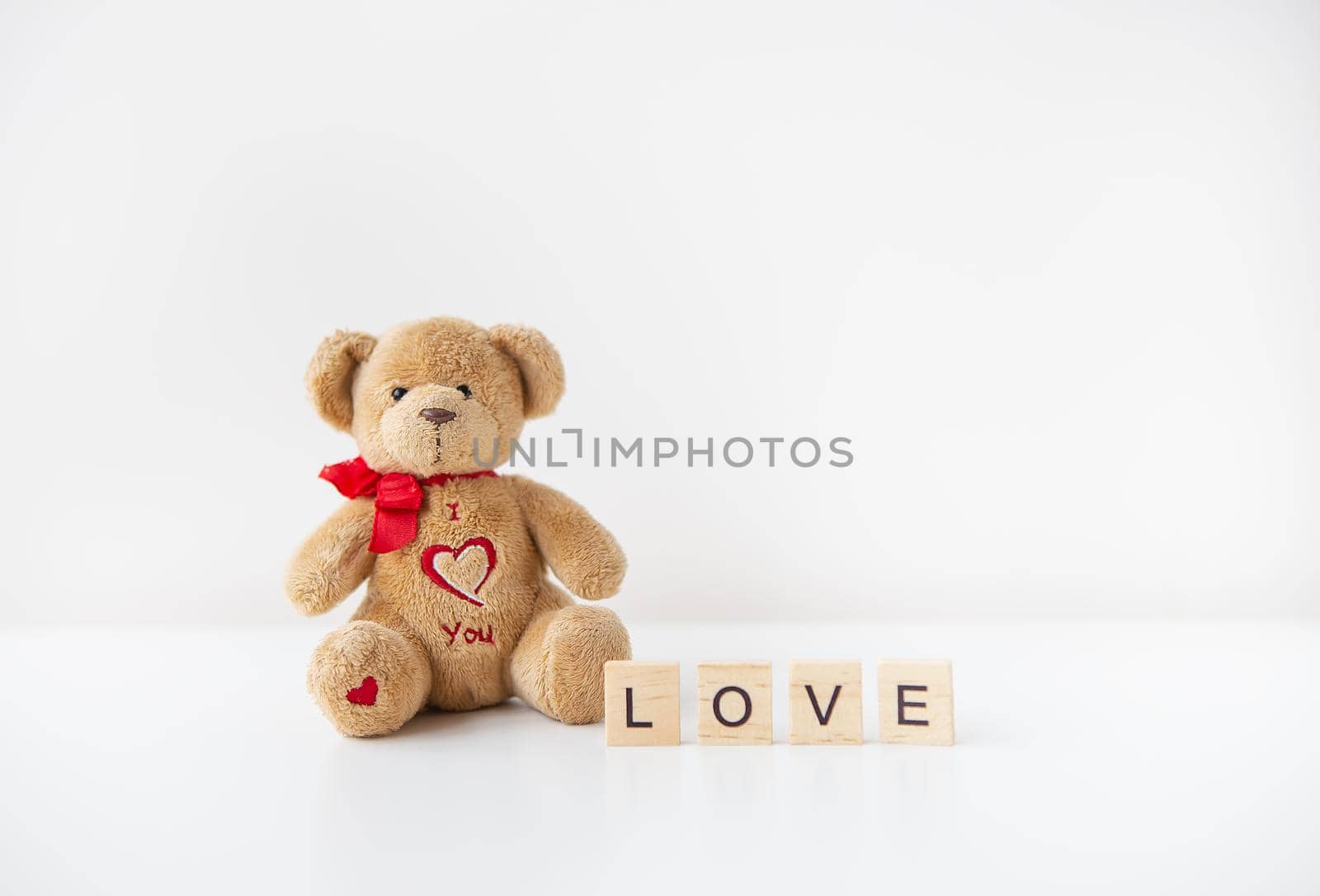 Cute toy teddy bear with a heart isolated on a white background. Love lettering, Valentine's Day holiday concept