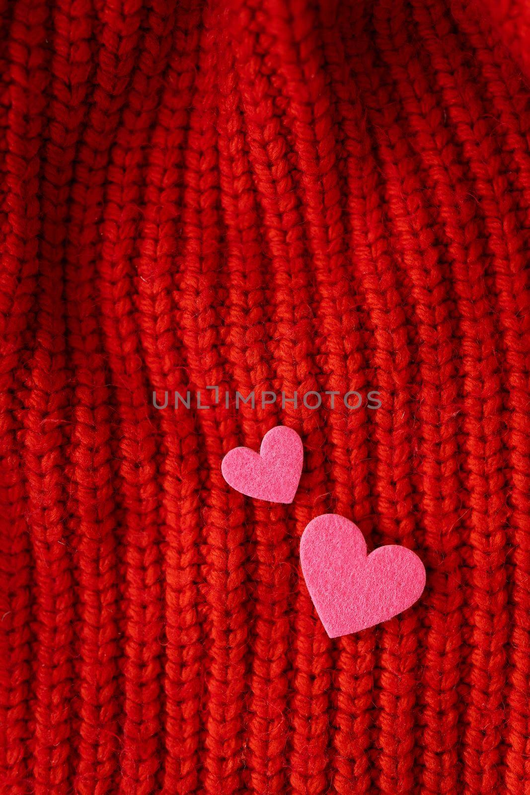 Decorative pink heart on a red knitted background, top view. Place for an inscription, vertical photo. by sfinks