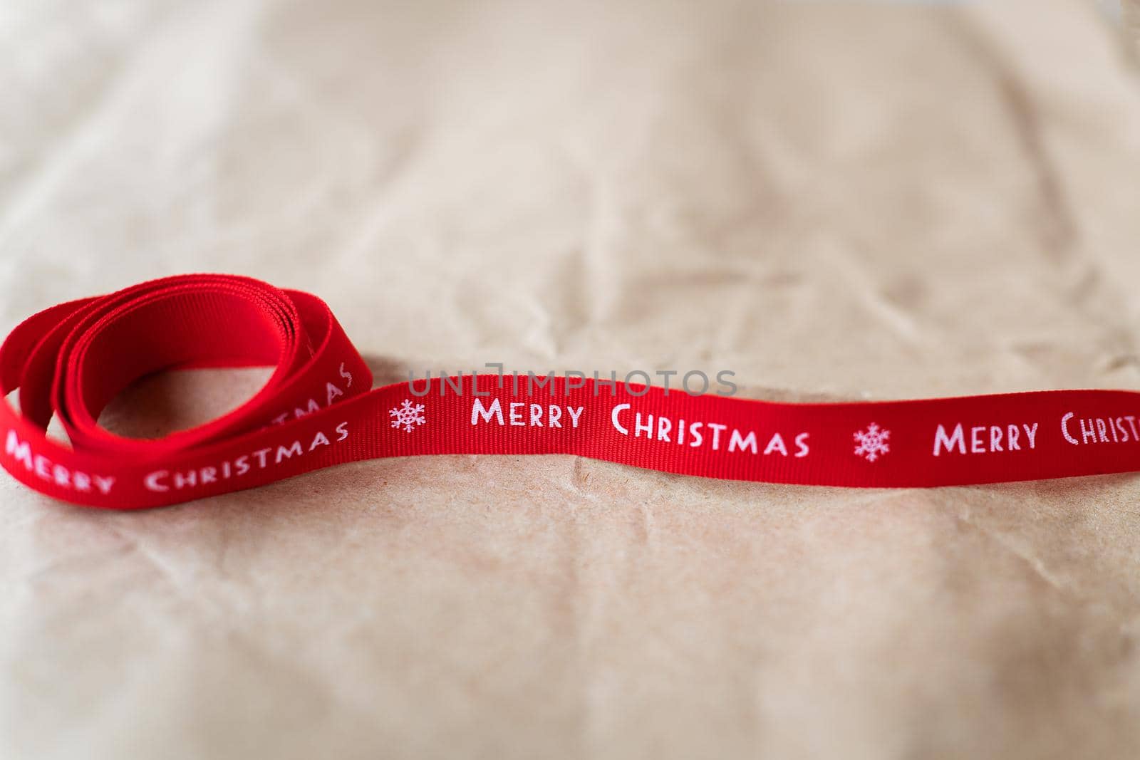 Red ribbon with the inscription Merry Christmas spread out on craft paper. Place for an inscription