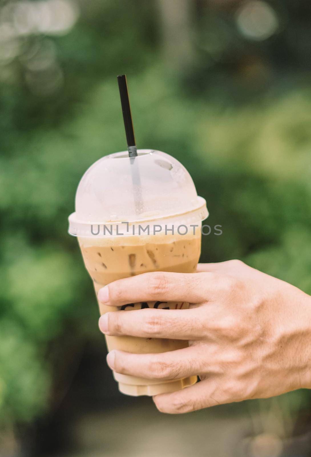 Hand hold iced latte coffee in a glass. cold summer drink background