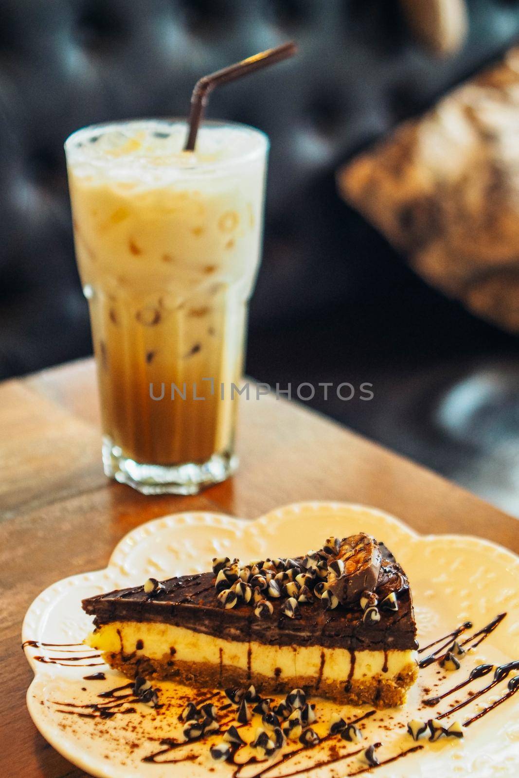 A slide of chocolate cake with iced latte coffee in a  tall glass. cold summer drink background