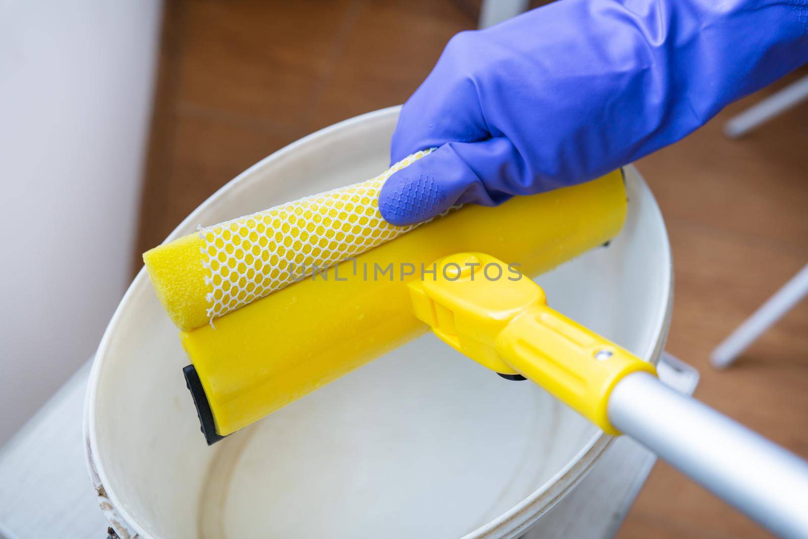 House cleaning and cleaning concept. A young girl in purple gloves squeezes water out of a mop. by sfinks