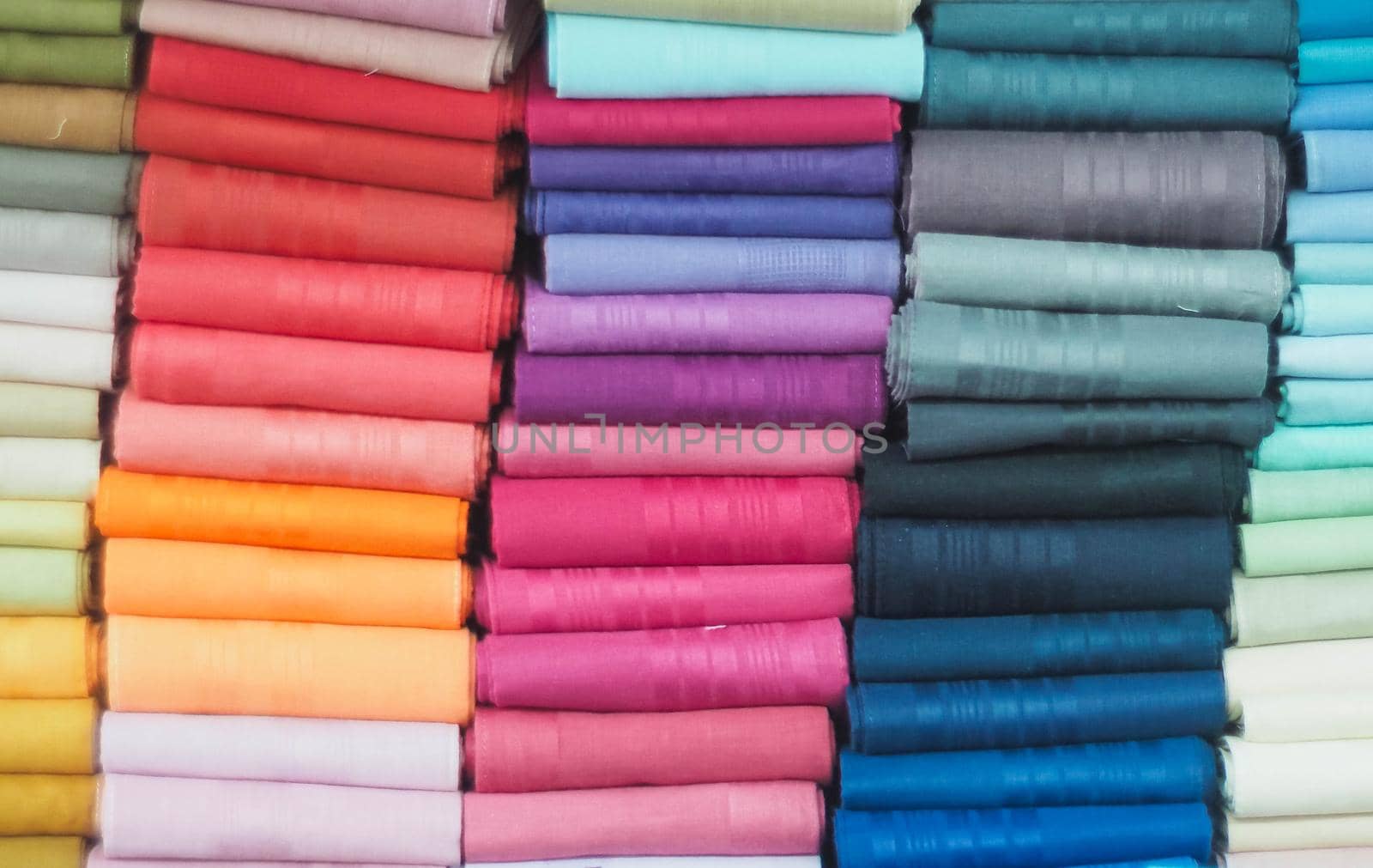 colorful fabric rolls in textile shop industry.Rolls of bright colored fabric by Petrichor