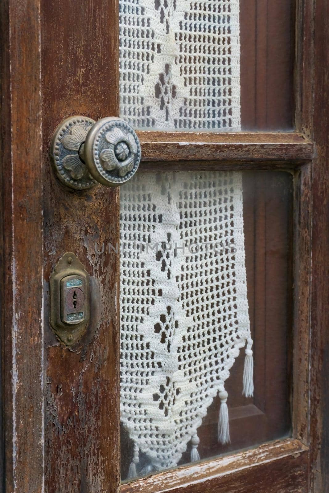Antique wooden door with a glass window and a white knitted napkin behind it close up