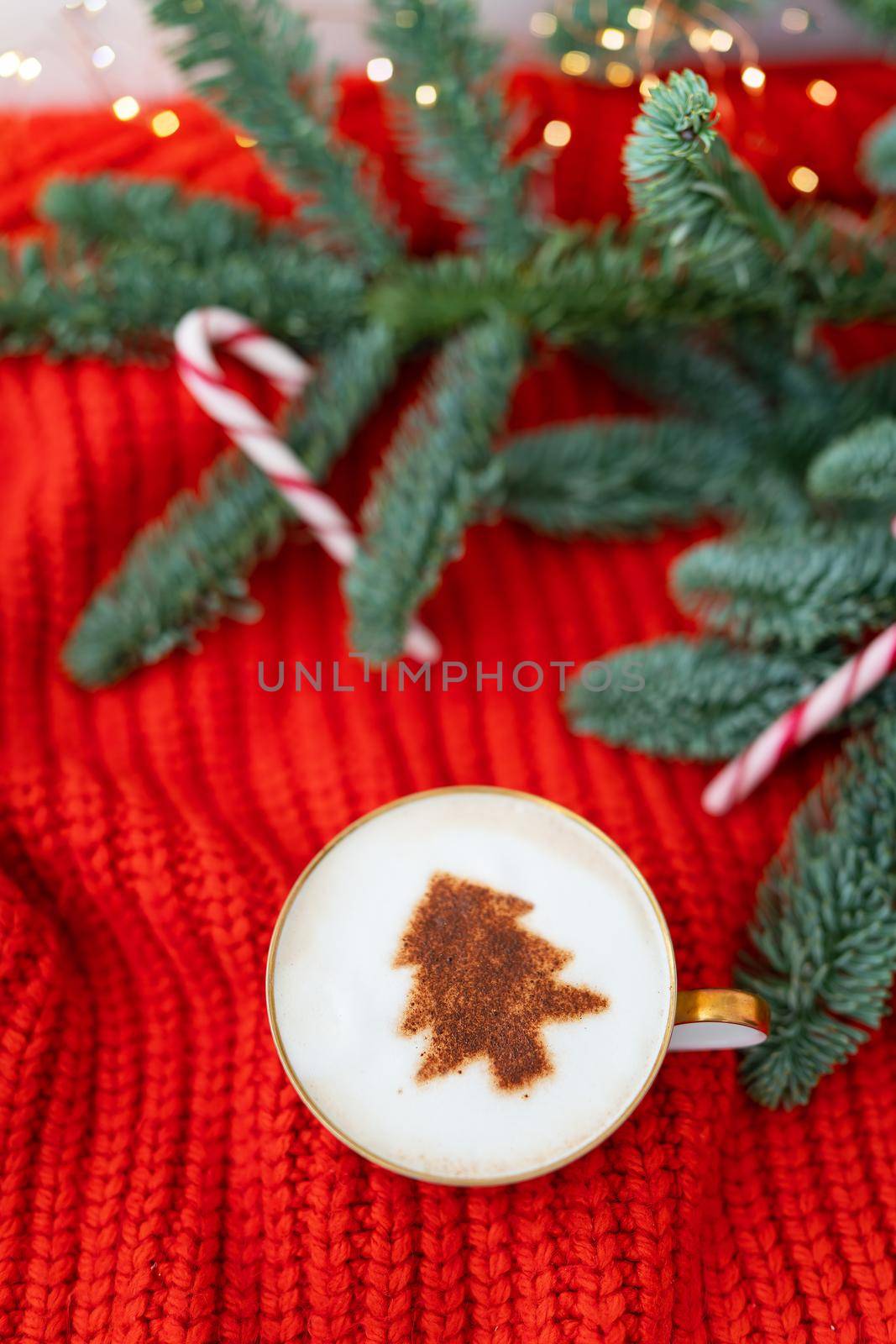 Christmas composition made of Norwegian Nobilis pine and decorated with lights and candy canes in the form of a cane. A cup of cappuccino with a Christmas tree pattern. Christmas and New Year concept. by sfinks