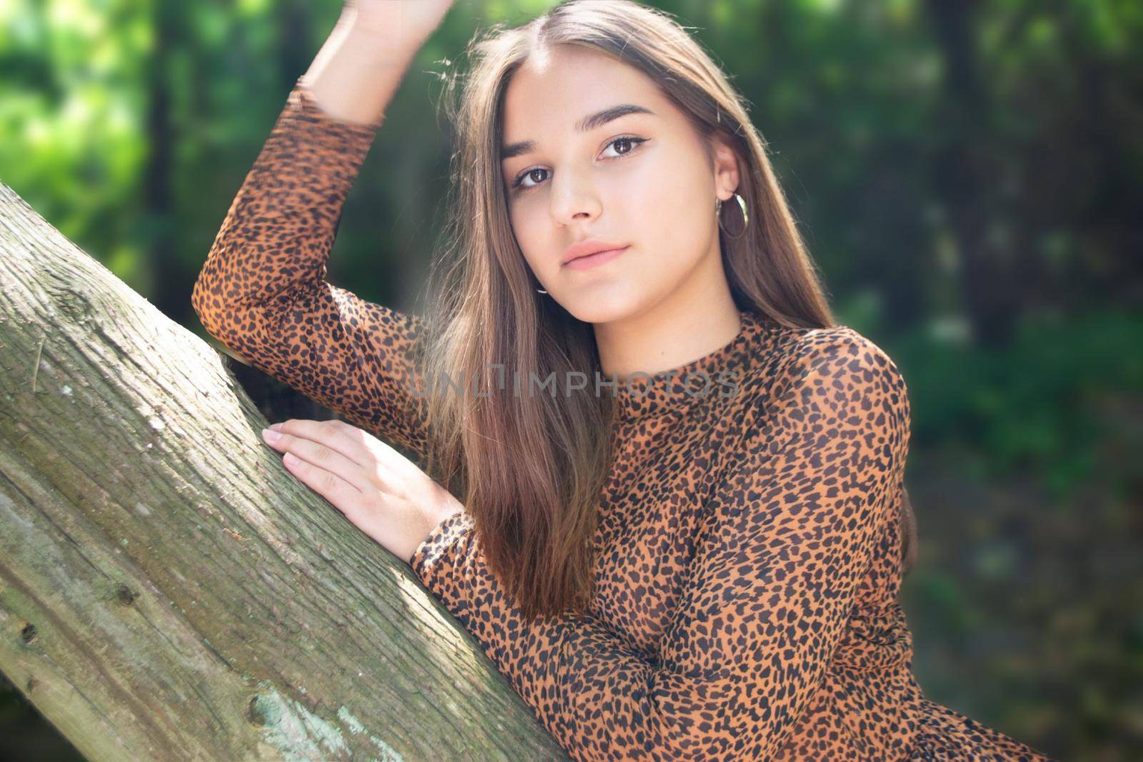 Emotional girl teenager with long hair hairstyle braids in a green shirt sits on a bench in the park. High quality photo