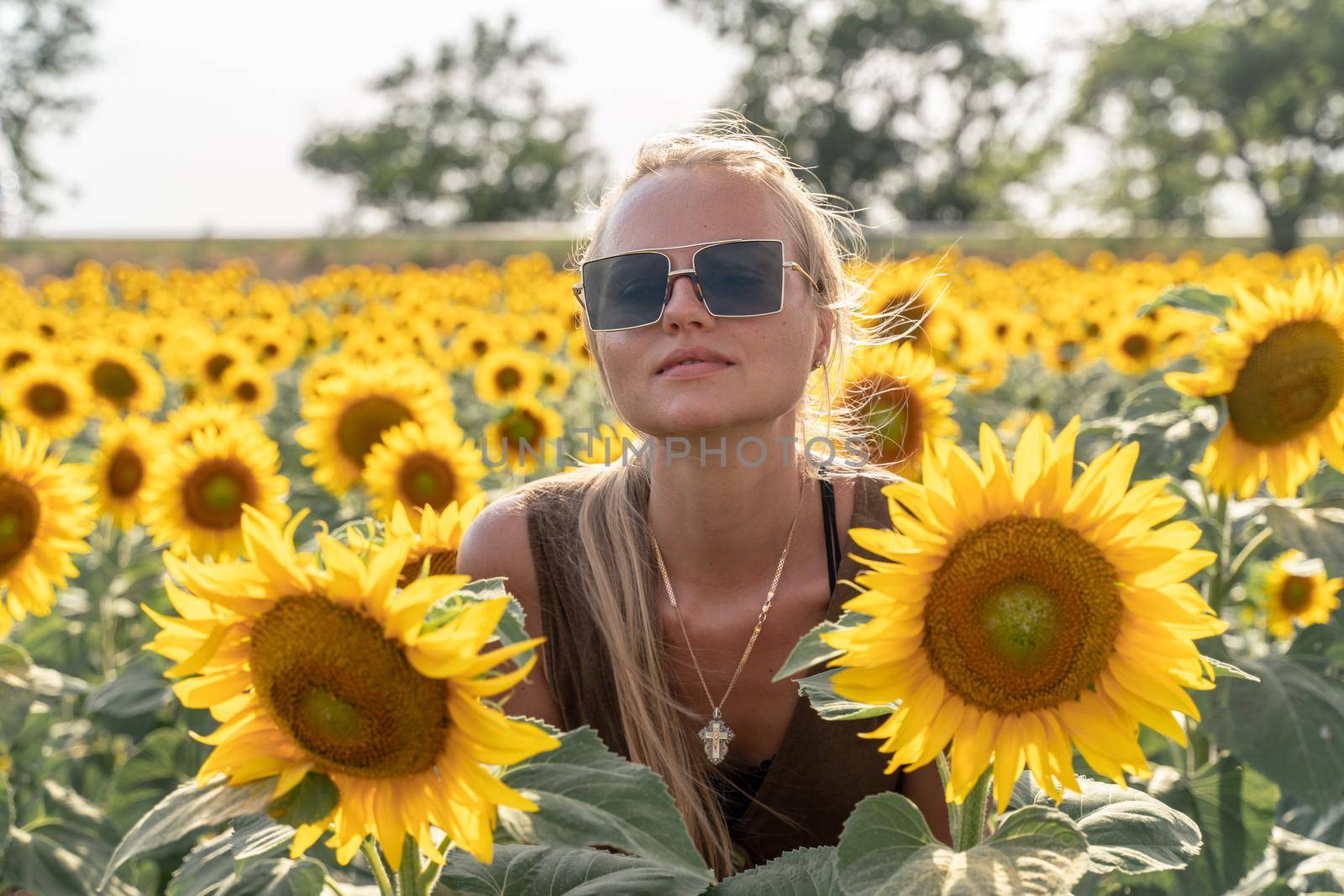 Beautiful woman in sunflower field at sunset enjoying summer nature. Attractive blonde with long healthy hair. by Matiunina