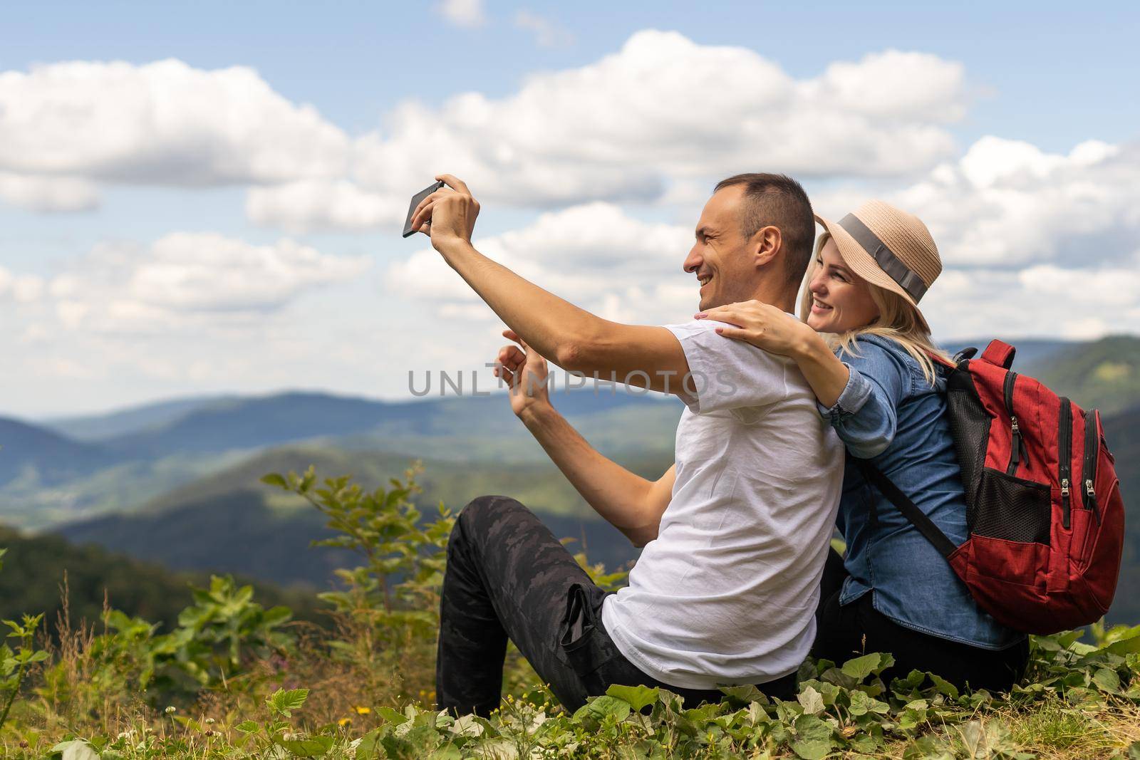 Hikers with backpacks relaxing on top of a mountain and enjoying the view by Andelov13