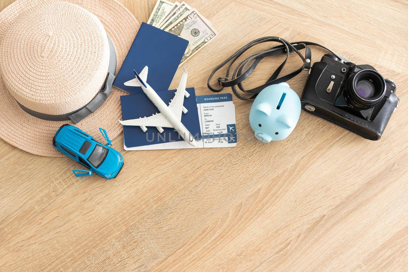 passport, tickets, toy plane, camera, piggy bank on wooden floor