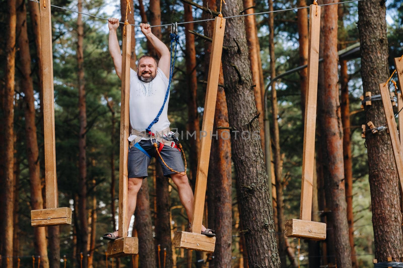 A man overcomes an obstacle in a rope town. A man in a forest rope park.