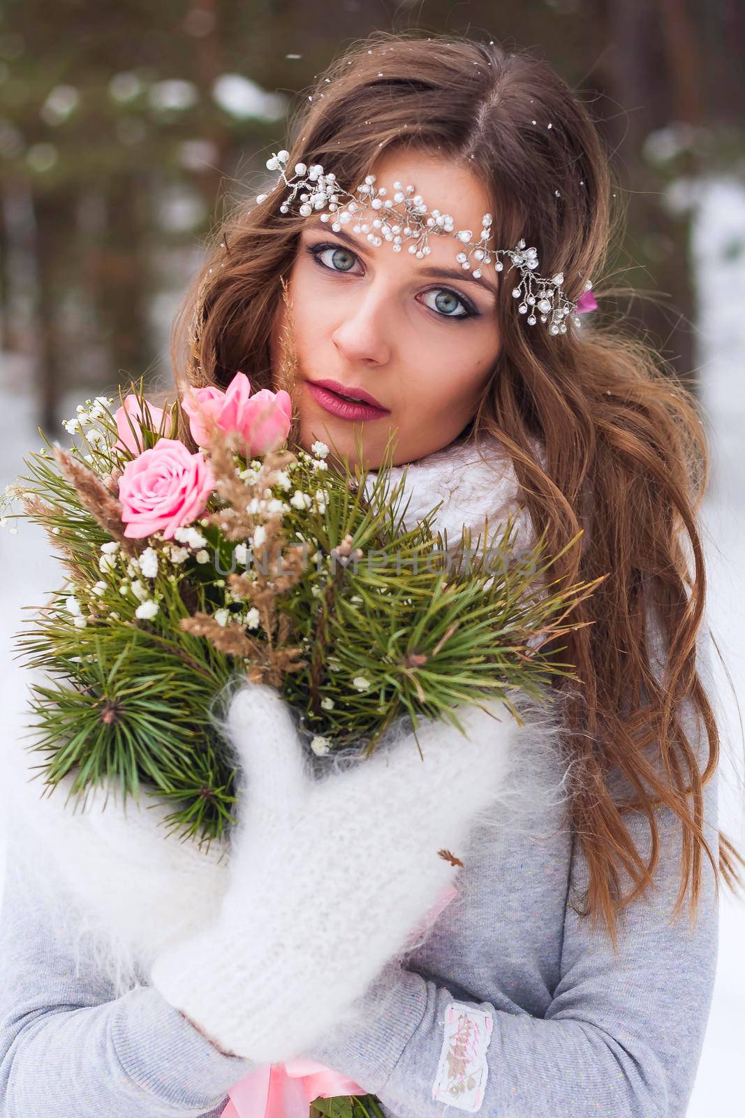 Beautiful bride in a white dress with a bouquet in a snow-covered winter forest. Portrait of the bride in nature.Beautiful bride in a white dress with a bouquet in a snow-covered winter forest. Portrait of the bride in nature.