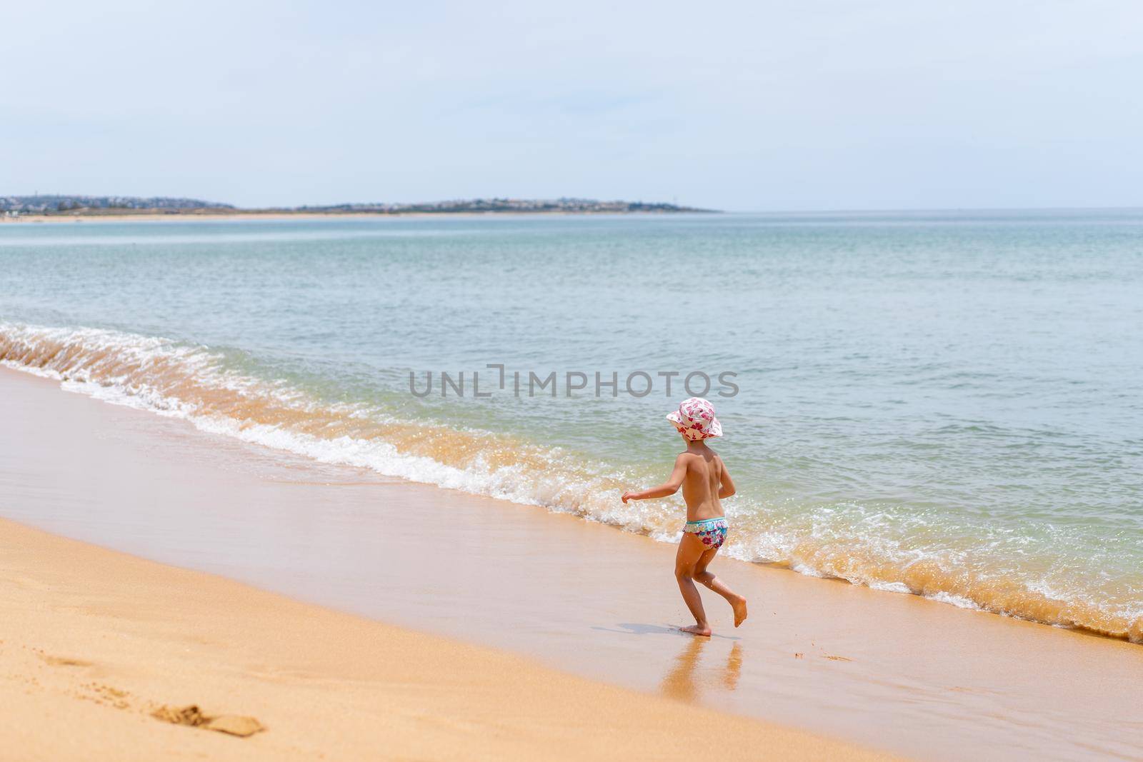 Back view of adorable little girl at sandy Atlantic ocean beach during summer. High quality FullHD footage