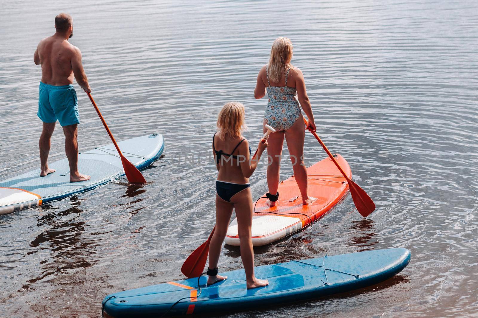 The family spends time together swimming on sup boards on the lake.