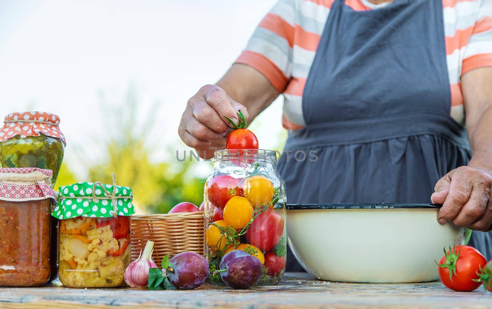 Senior woman preserving vegetables in jars. Selective focus. Food.