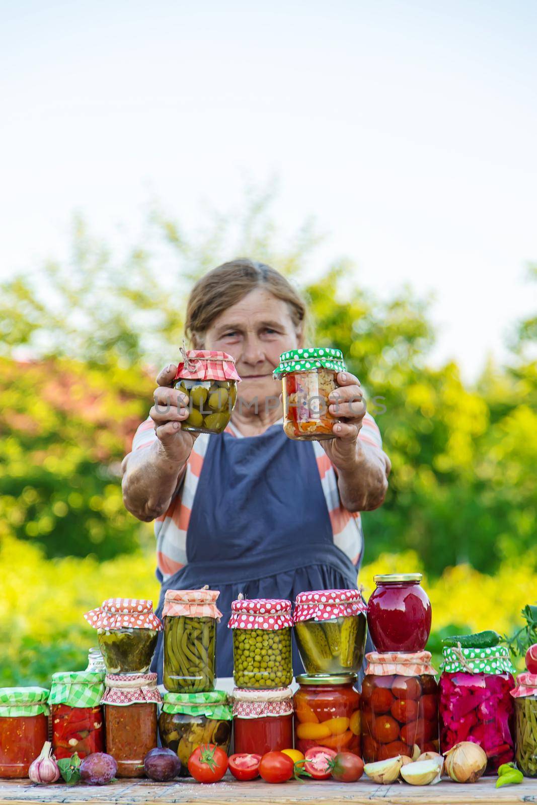 Senior woman preserving vegetables in jars. Selective focus. Food.