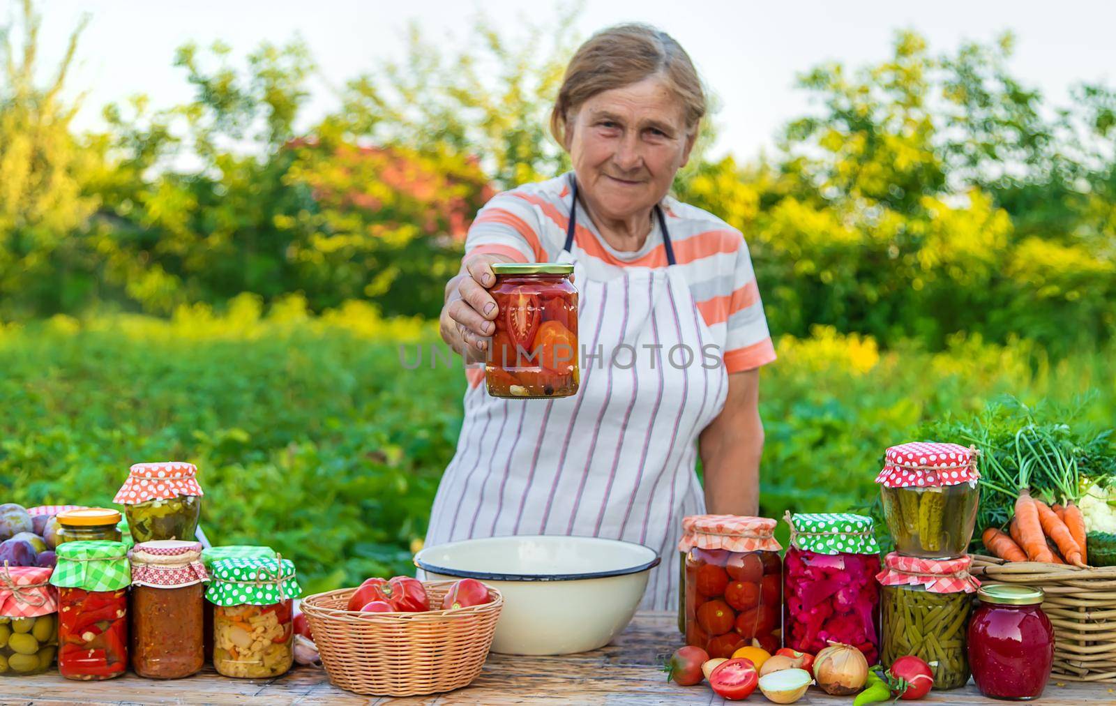 Senior woman preserving vegetables in jars. Selective focus. Food.