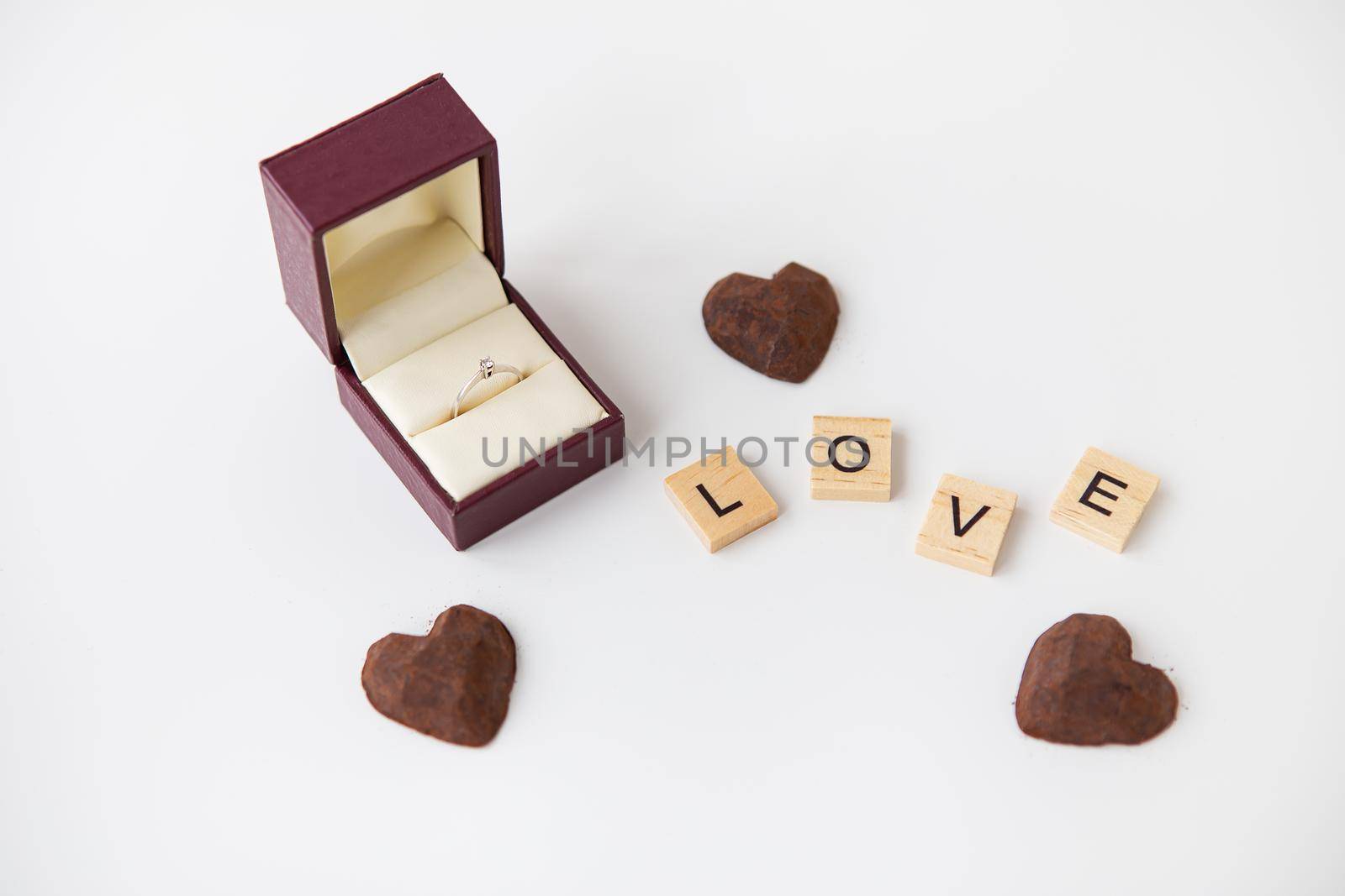 The inscription in wooden letters love, small truffle sweets in the form of a heart. Diamond ring box - marriage proposal