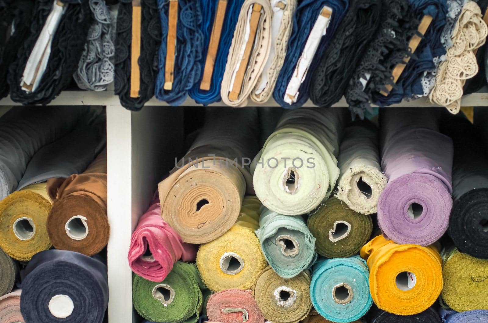 colorful fabric rolls in textile shop industry.Rolls of bright colored fabric by Petrichor