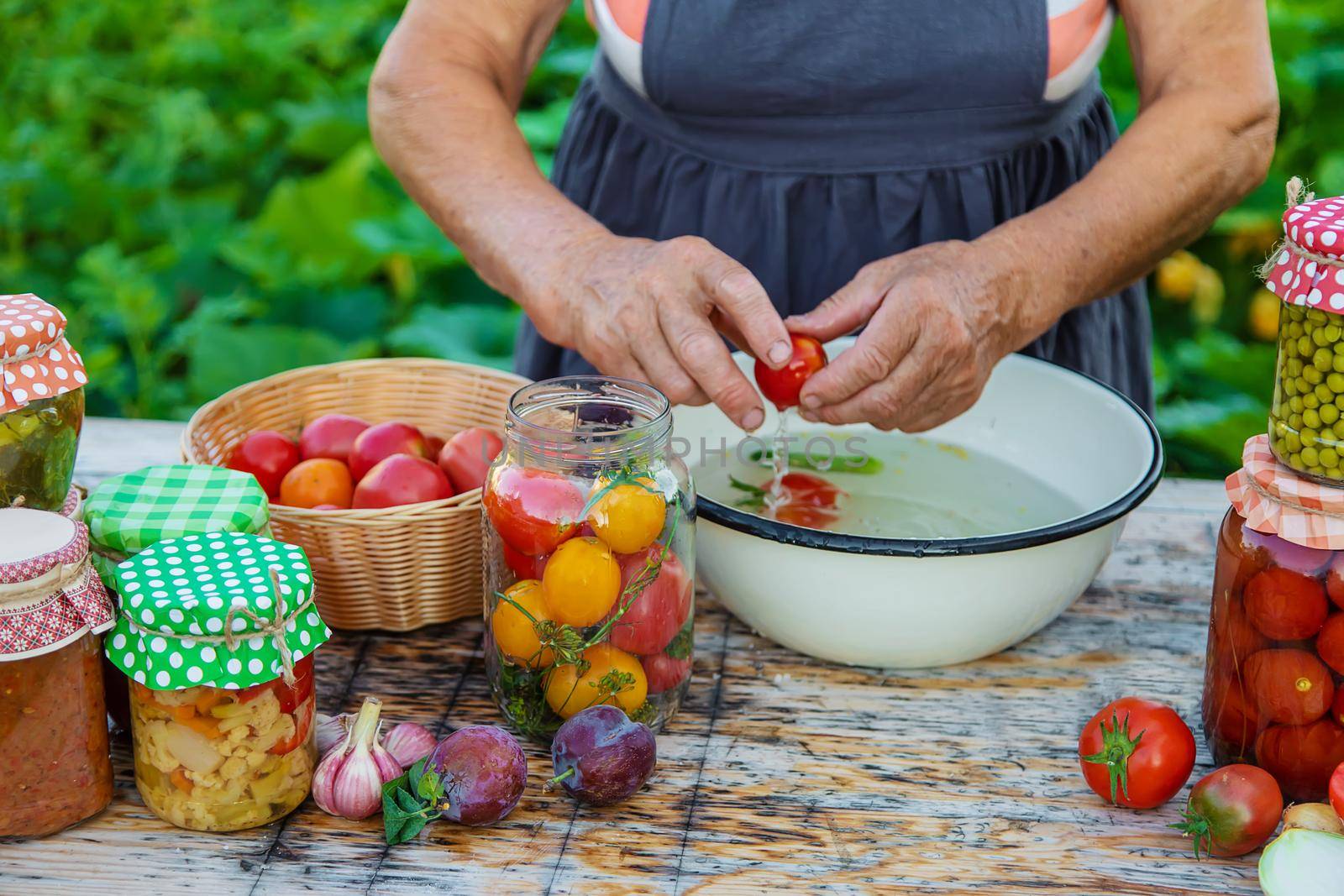 Senior woman preserving vegetables in jars. Selective focus. Food.