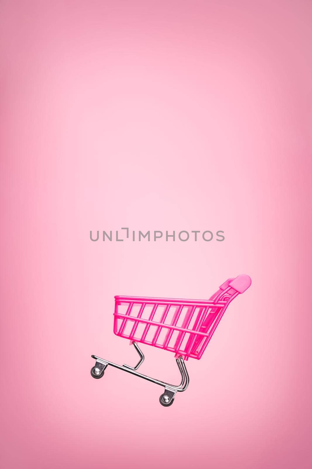 Empty trolley cart isolated pink background. Pink shopping trolley supermarket concept. Toy pink concept sales online shopping cart supermarket sales shopping symbol. Sale cart shop online. E commerce